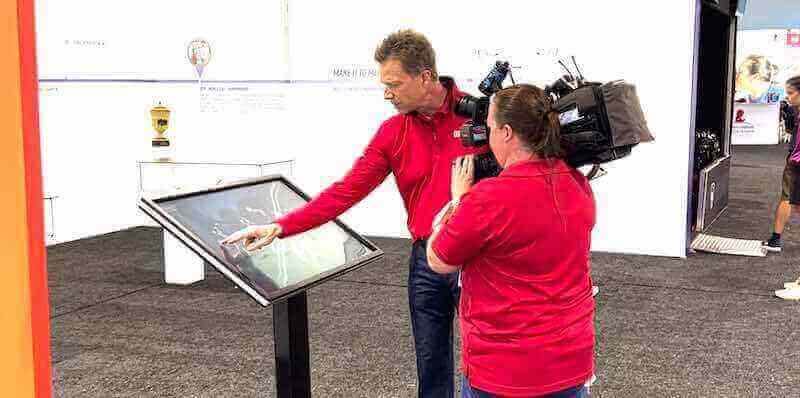 Filming interactive kiosk demonstration Camera operator filming interactive touchscreen kiosk demonstration